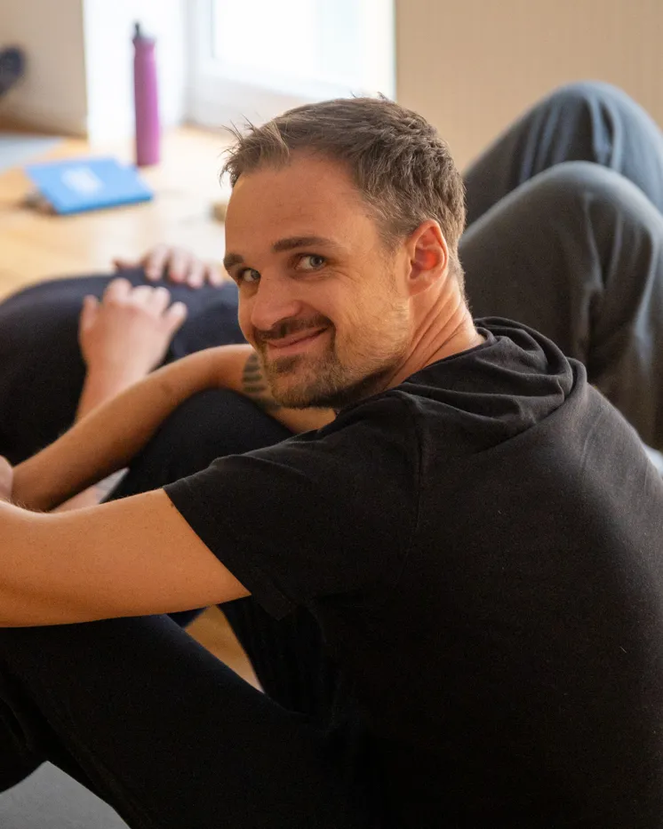 Johannes Link sitzt lächelnd beim Workshop-Wochenende zwischen den Teilnehmern